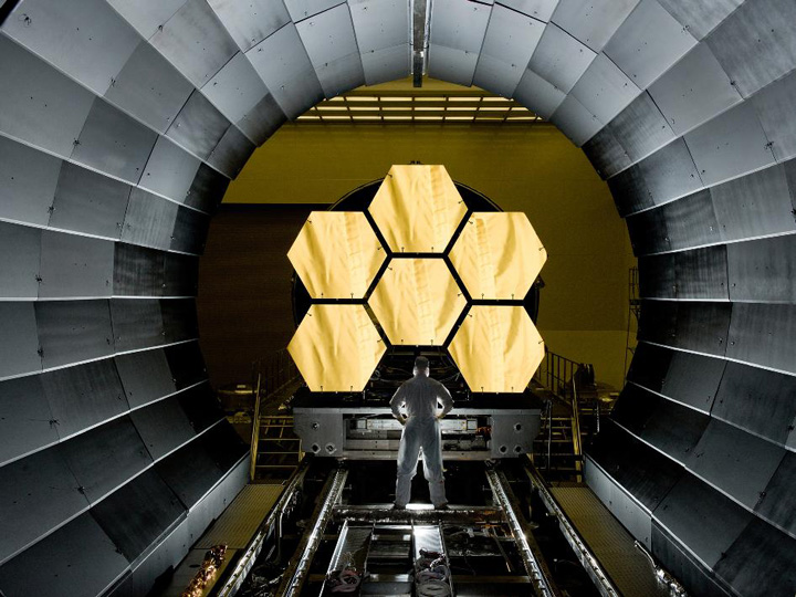 An engineer standing by the primary mirrors of the JWST.